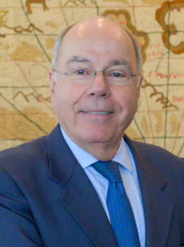Smiling portrait of Mauro Vieira in a blue suit and tie before an antique map