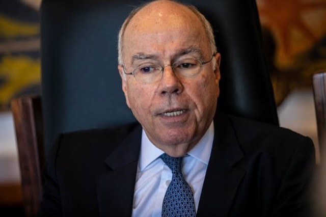 Mauro Vieira seated in a high-backed chair, gesturing as he speaks during an interview in an office