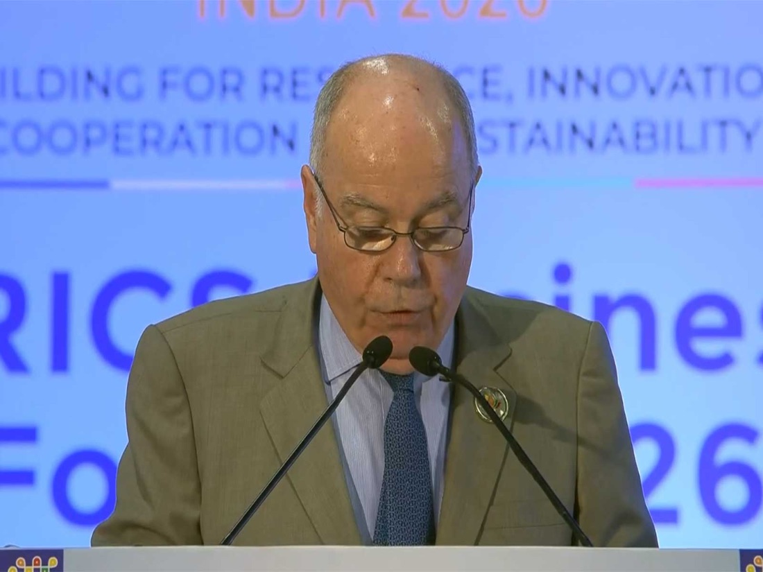 Mauro Vieira reading a speech at a lectern with two microphones, a blue backdrop reading BRICS Business Forum 2026 and India 2026 behind him