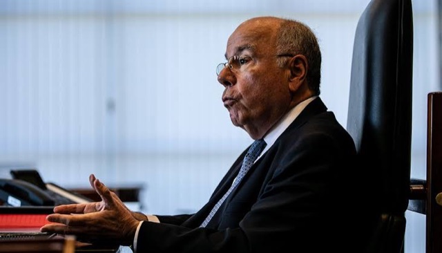 Mauro Vieira in profile, seated at his desk, gesturing as he speaks
