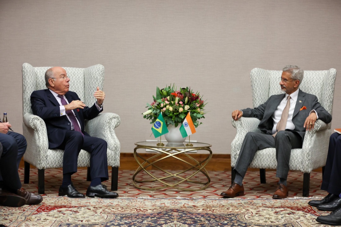 Mauro Vieira and India’s External Affairs Minister seated in armchairs facing each other, with Brazilian and Indian table flags and flowers between them