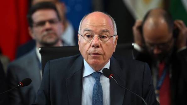 Mauro Vieira seated at a conference table with microphones, delegates behind him