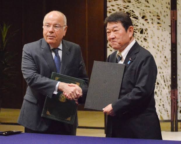 Mauro Vieira and a counterpart shake hands while each holds a signed document folder
