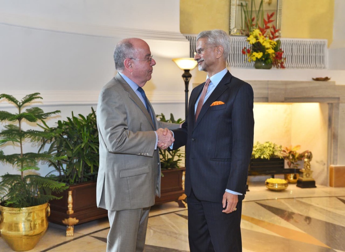 Mauro Vieira shaking hands with India’s External Affairs Minister in an ornate reception hall with plants and brass urns