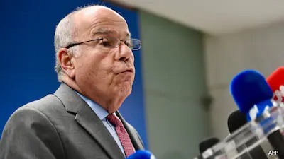 Mauro Vieira speaking at a press conference, broadcast microphones in the foreground